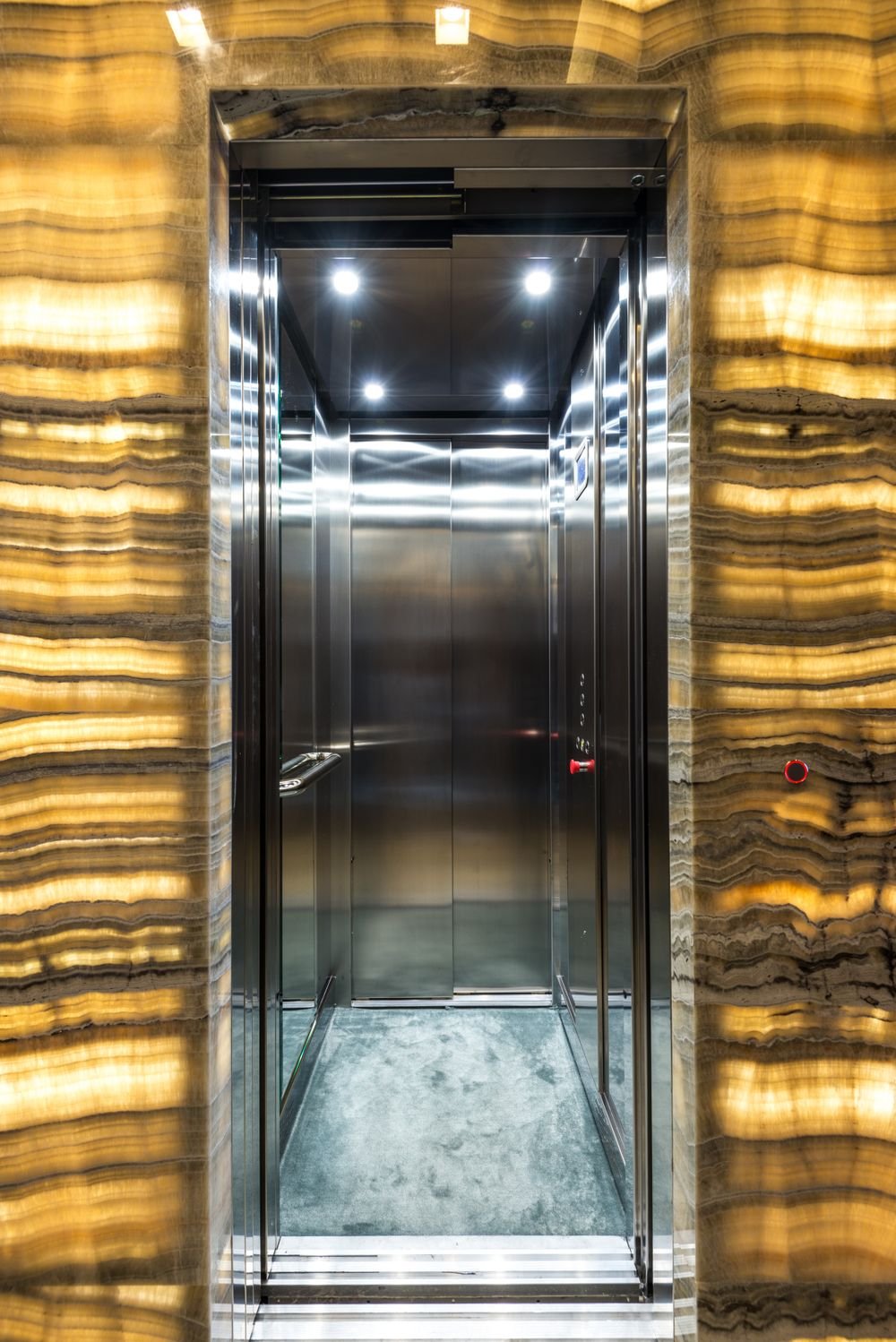 Gold-toned marble surrounding a stainless steel elevator cabin